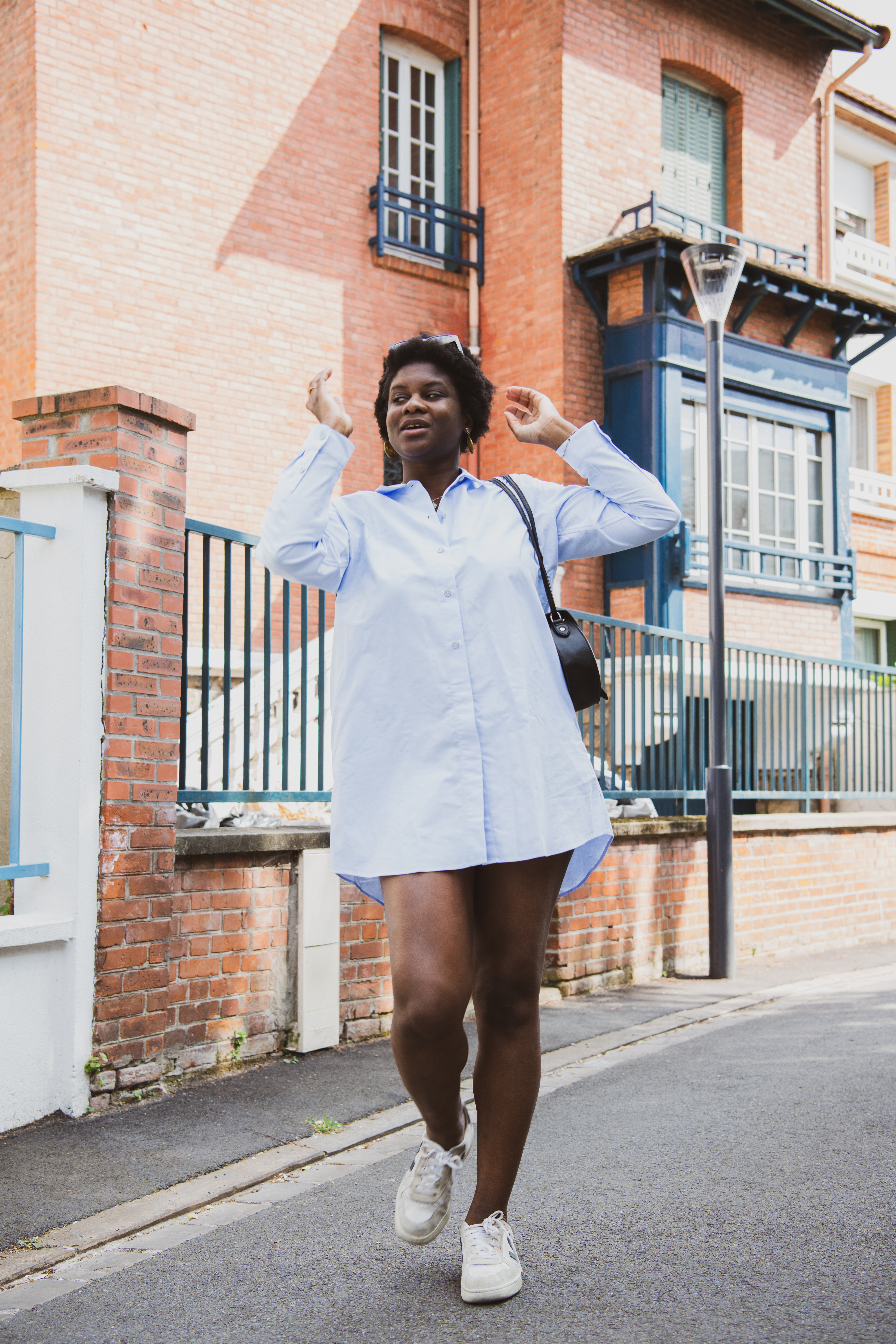 Adelana porte la robe Oxford-Long-Shirt d'Organic Basics. Elle marche dans la rue